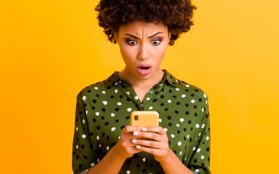 Photo of a woman looking at her phone with a shocked expression to illustrate the article How to Stop Doomscrolling